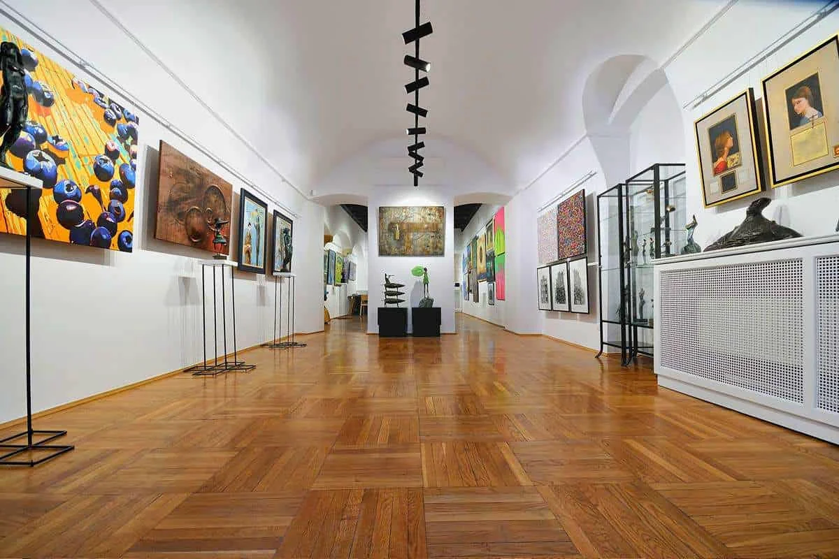 A long, vaulted gallery room with paintings on the walls and sculptures in display cases